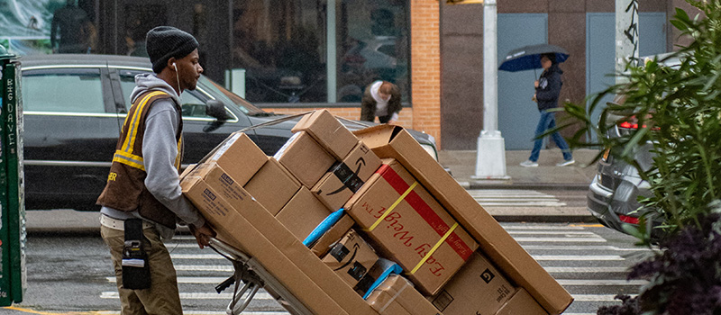 Man delivering packages in the city, packages of different sizes stacked on a dolly cart