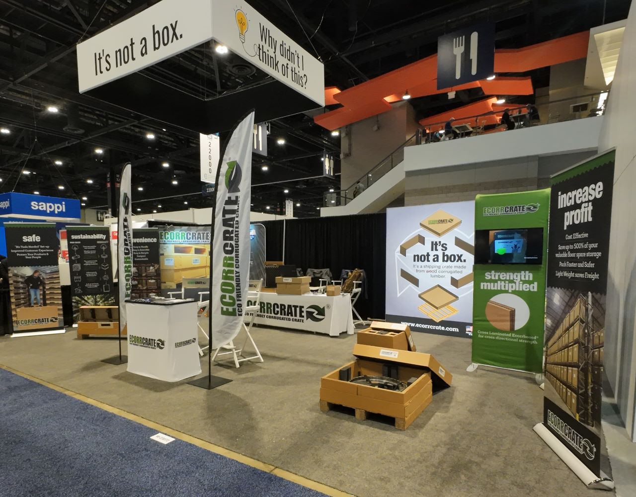 Ecorrcrate's booth at the MRO Americas Pack Expo show 2024 from right angle - showing corrugated ecorrcrates standing posters: Increase Profit, Strength multiplied, It's not a Box, Safe, Sustainability, Convenience; and Why didn't I think of this?